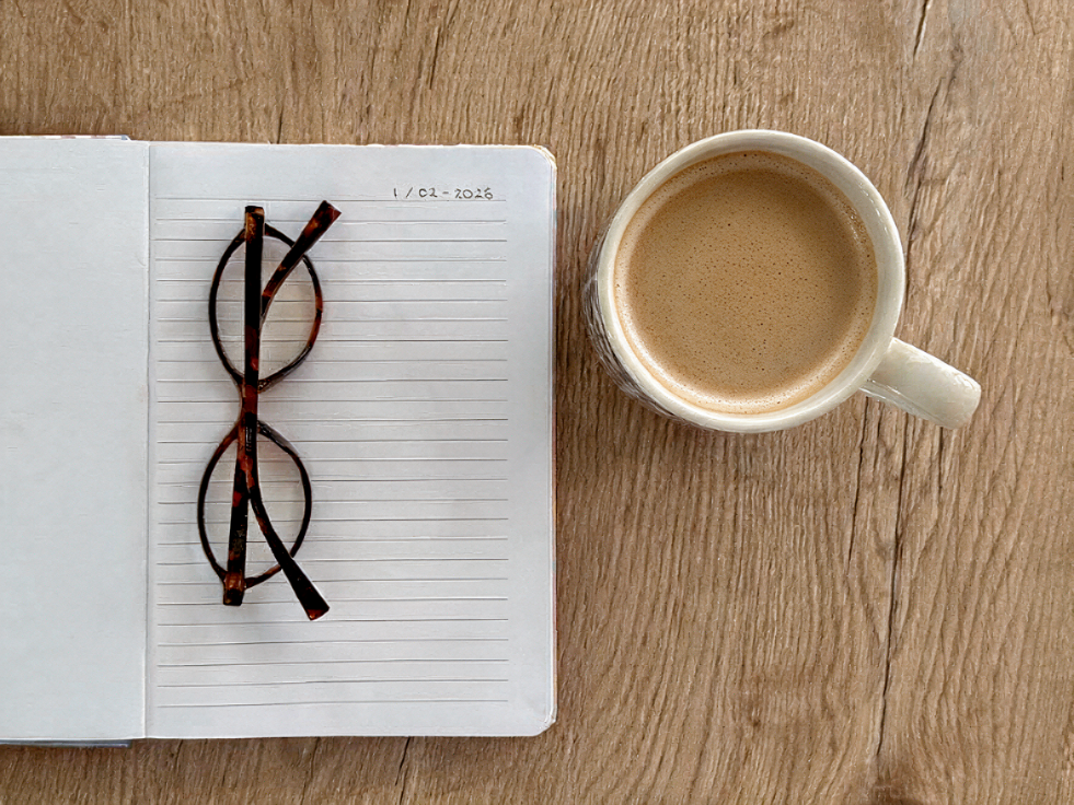 A latte and an open notebook on a quiet morning table